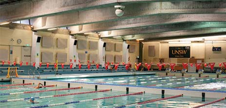 Image of the UNSW Fitness and Aquatic Centre Pool with lanes split in half to show 25m pool. UNSW sign in background and red bunting across pool.